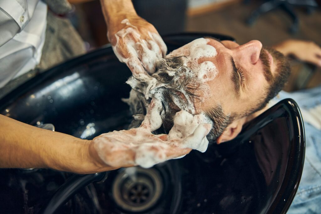 Man krijgt een professionele haarwasbehandeling in een kapsalon met rijk schuimende shampoo voor een gezonde hoofdhuid en schoon haar.